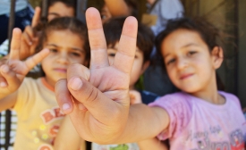 Photo by Trocaire | CC BY 2.0 Syrian refugee children at a half-built apartment block near Reyfoun in Lebanon, close to the border with Syria, give the peace sign. The families fled Syria due to the war and are now living on a building site. (Photo: Eoghan Rice)